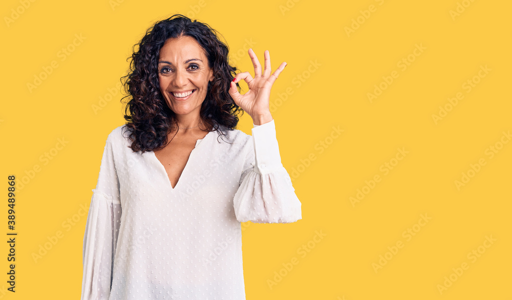 Middle age beautiful woman wearing casual sweater smiling positive doing ok sign with hand and fingers. successful expression. Middle age beautiful woman wearing casual sweater smiling positive doing ok sign with hand and fingers. successful expression.