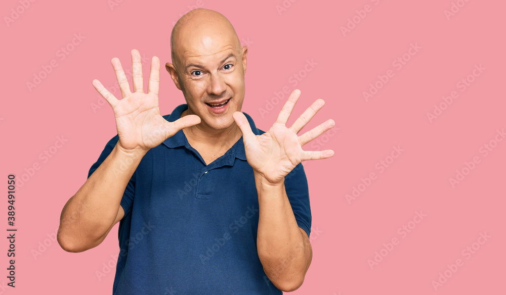 Middle age bald man wearing casual clothes showing and pointing up with fingers number ten while smiling confident and happy. Middle age bald man wearing casual clothes showing and pointing up with fingers number ten while smiling confident and happy.