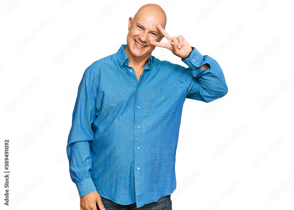 Middle age bald man wearing casual clothes doing peace symbol with fingers over face, smiling cheerful showing victory Middle age bald man wearing casual clothes doing peace symbol with fingers over face, smiling cheerful showing victory
