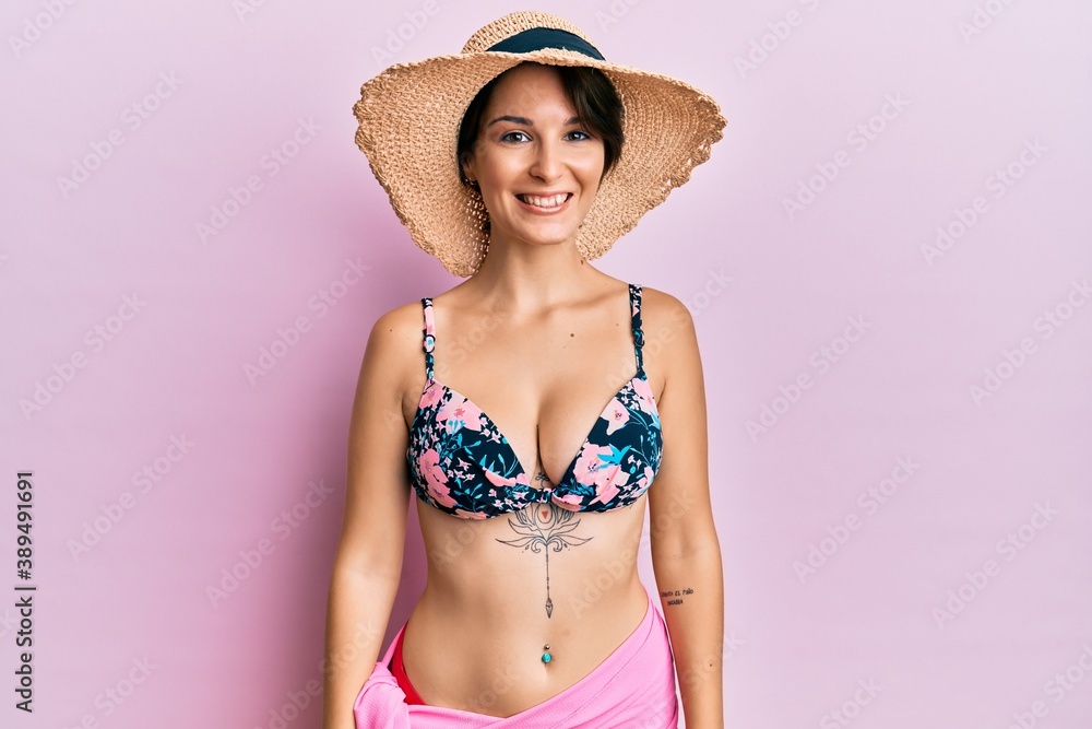 Young brunette woman with short hair wearing bikini and hat with a happy and cool smile on face. lucky person. Young brunette woman with short hair wearing bikini and hat with a happy and cool smile on face. lucky person.