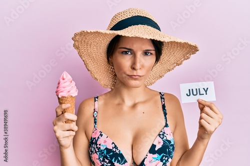 Young brunette woman with short hair holding ice cream and july paper skeptic and nervous, frowning upset because of problem. negative person.