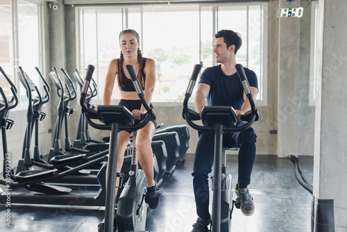 Male and female athletes talk about exercise, cycling in the gym. They wear sportswear to exercise.