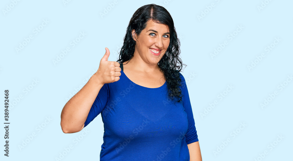Plus size brunette woman wearing casual clothes smiling happy and positive, thumb up doing excellent and approval sign Plus size brunette woman wearing casual clothes smiling happy and positive, thumb up doing excellent and approval sign