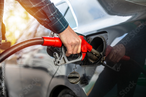 close up worker hand holding nozzle fuel fill oil into car tank at pump gas station.Car refueling on the petrol station. Male hand filling gasoline to the car.