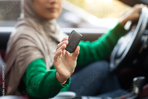 Unrecognizable muslim woman showing auto key, sitting on driver's seat