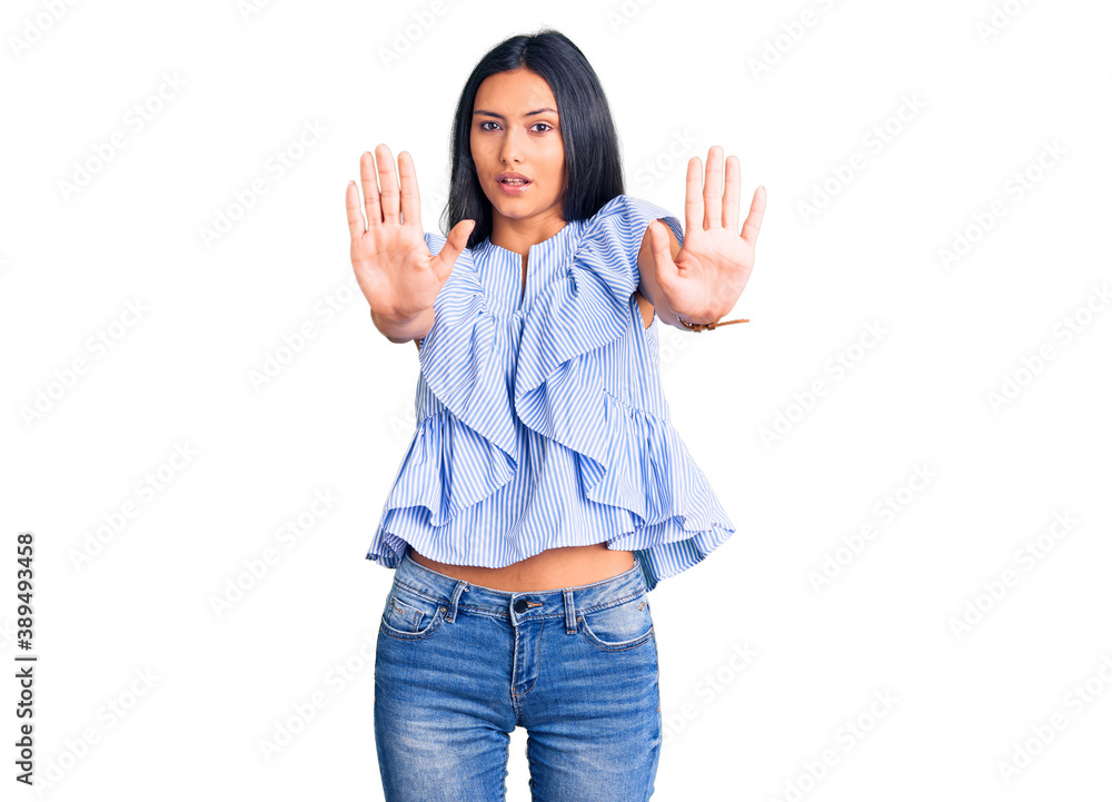 Young beautiful latin girl wearing casual clothes doing stop gesture with hands palms, angry and frustration expression