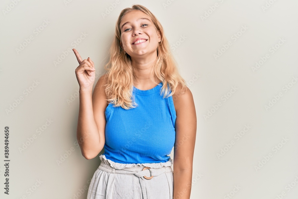 Young blonde girl wearing casual clothes pointing finger up with successful idea. exited and happy. number one. Young blonde girl wearing casual clothes pointing finger up with successful idea. exited and happy. number one.