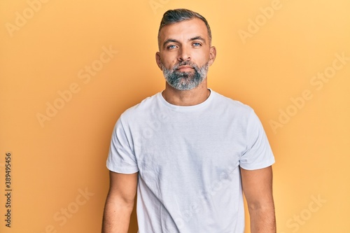 Middle age handsome man wearing casual white tshirt relaxed with serious expression on face. simple and natural looking at the camera. © Krakenimages.com