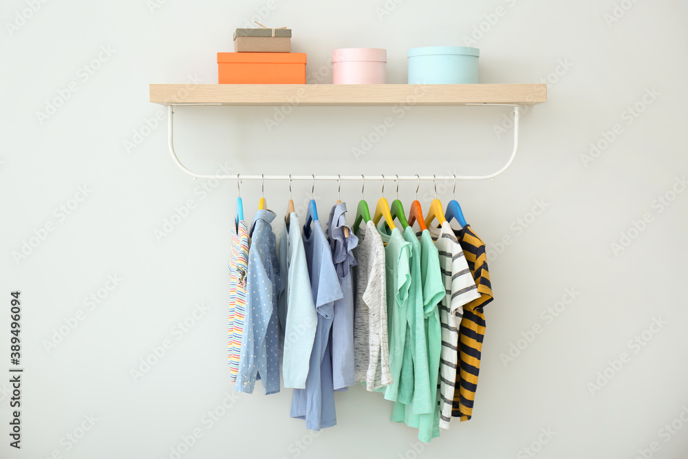 Rack with different clothes on light background