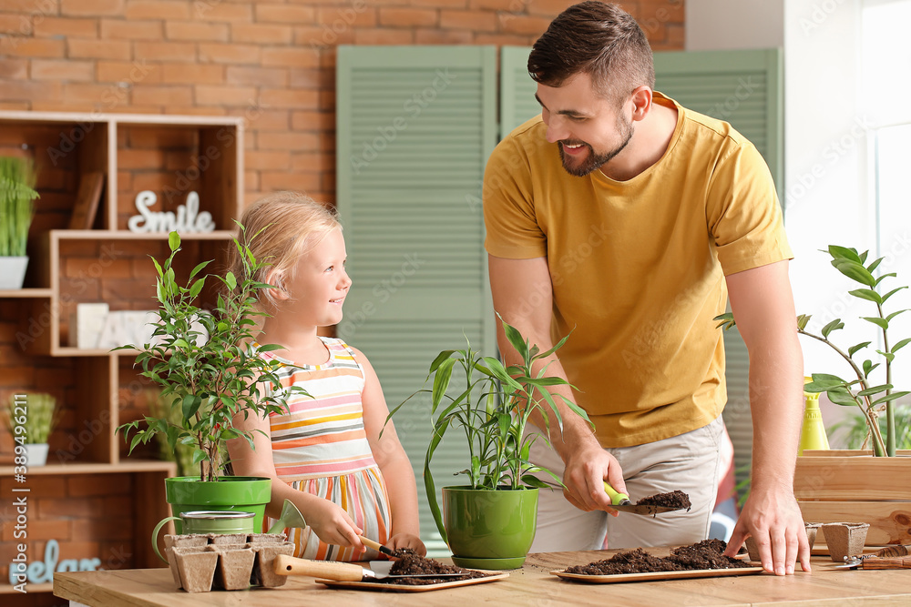 Young father with daughter setting out plants at home Young father with daughter setting out plants at home
