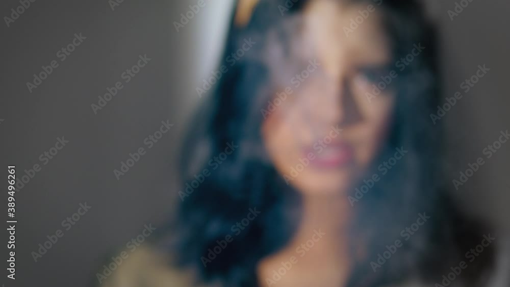 Brunette woman smokes and casts a shadow on a white wall.
Front view Brunette woman smokes and casts a shadow on a white wall.
Front view