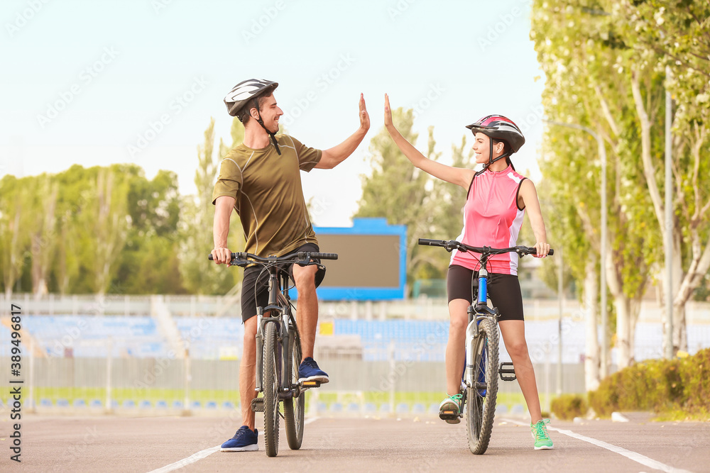 Male and female cyclists giving each other high-five outdoors