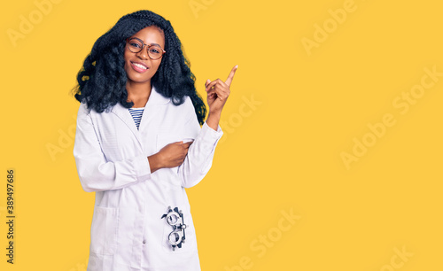 Beautiful african american optician woman with optometry glasses smiling happy pointing with hand and finger to the side photo