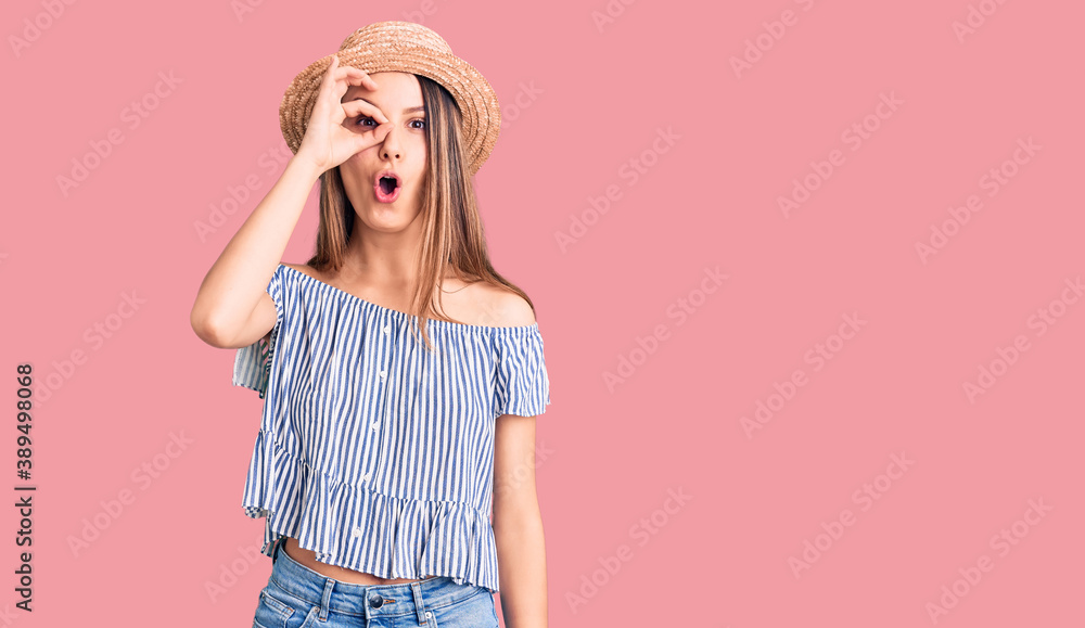Young beautiful girl wearing hat and t shirt doing ok gesture shocked with surprised face, eye looking through fingers. unbelieving expression. Young beautiful girl wearing hat and t shirt doing ok gesture shocked with surprised face, eye looking through fingers. unbelieving expression.
