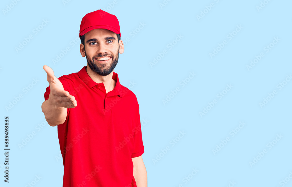 Young handsome man with beard wearing delivery uniform smiling cheerful offering palm hand giving assistance and acceptance. Young handsome man with beard wearing delivery uniform smiling cheerful offering palm hand giving assistance and acceptance.