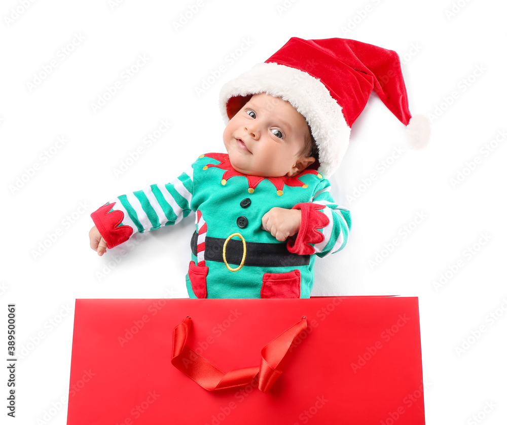 Cute little baby in Santa hat and with shopping bag on white background