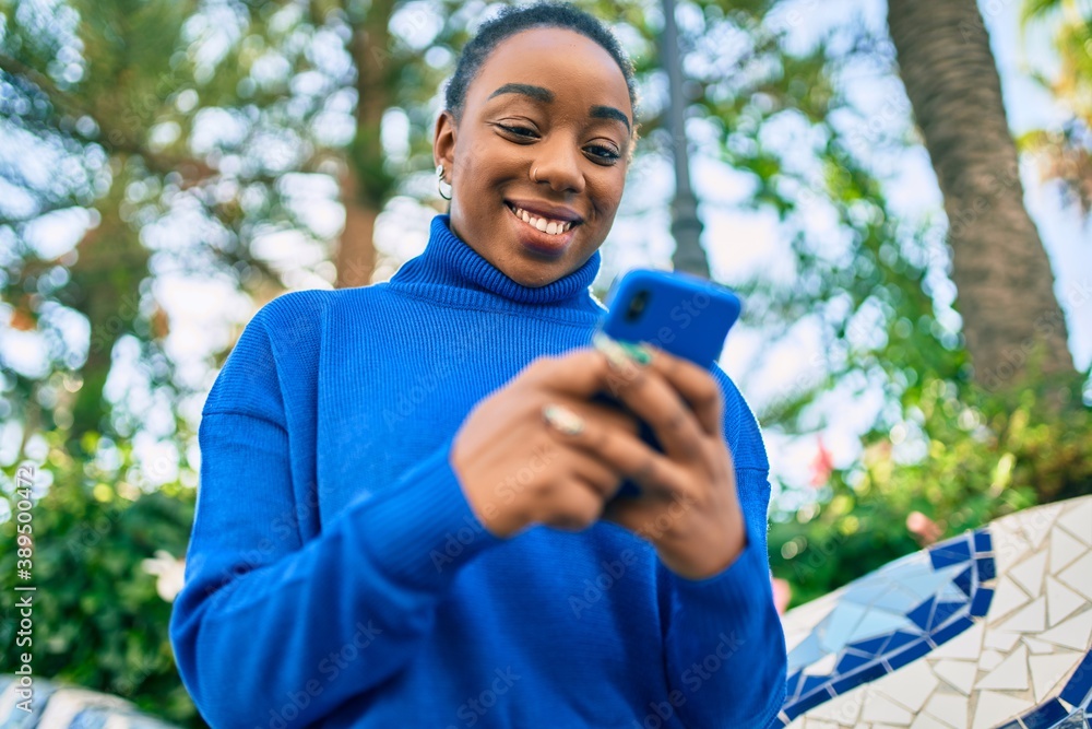 Young african american woman smiling happy using smartphone at the park. Young african american woman smiling happy using smartphone at the park.