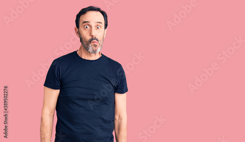 Middle age handsome man wearing casual t-shirt making fish face with lips, crazy and comical gesture. funny expression.