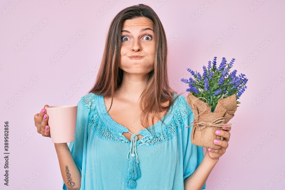 Beautiful caucasian woman drinking a cup of infused lavender puffing cheeks with funny face. mouth inflated with air, catching air. Beautiful caucasian woman drinking a cup of infused lavender puffing cheeks with funny face. mouth inflated with air, catching air.