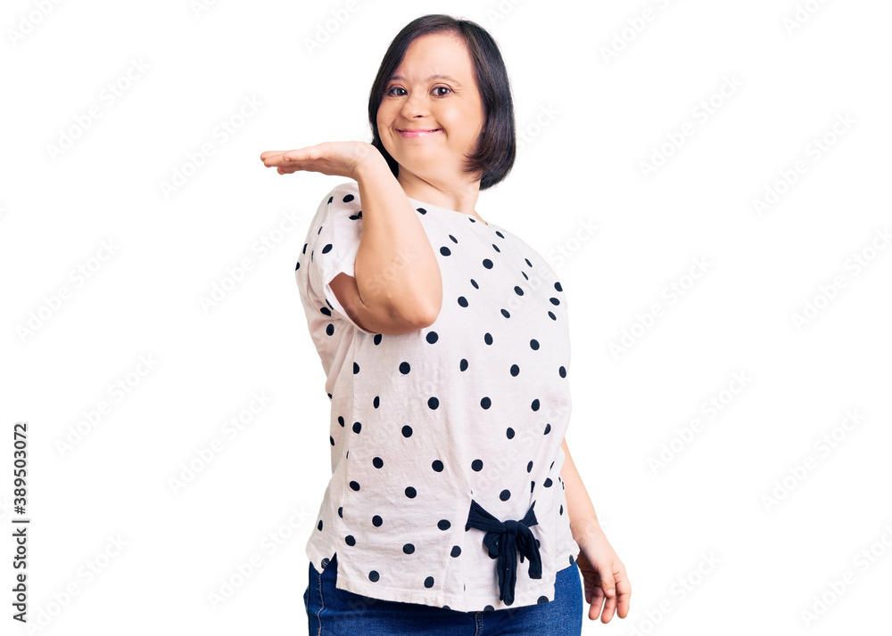 Brunette woman with down syndrome wearing casual clothes smiling cheerful presenting and pointing with palm of hand looking at the camera. Brunette woman with down syndrome wearing casual clothes smiling cheerful presenting and pointing with palm of hand looking at the camera.