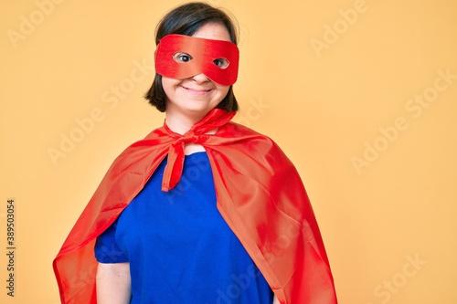 Brunette woman with down syndrome wearing super hero costume looking positive and happy standing and smiling with a confident smile showing teeth