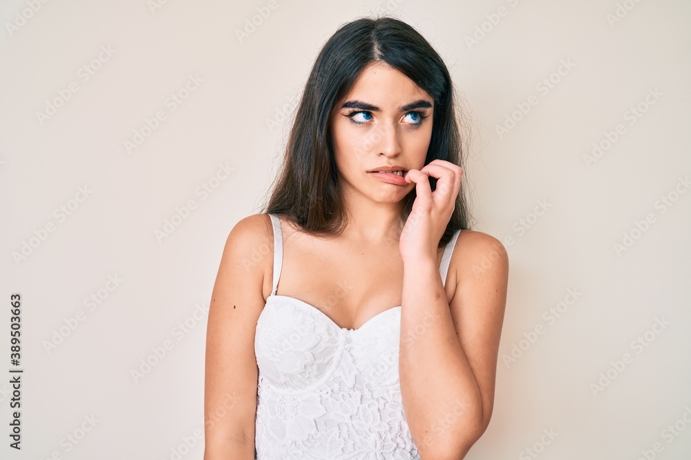 Brunette teenager girl posing elegant looking stressed and nervous with hands on mouth biting nails. anxiety problem. Brunette teenager girl posing elegant looking stressed and nervous with hands on mouth biting nails. anxiety problem.