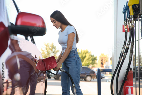 Young woman refueling car at self service gas station photo