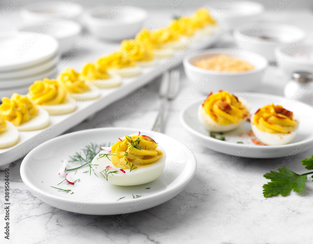 Close-up of Deviled Eggs with a Deviled Egg Bar behind on a Marble Countertop Close-up of Deviled Eggs with a Deviled Egg Bar behind on a Marble Countertop
