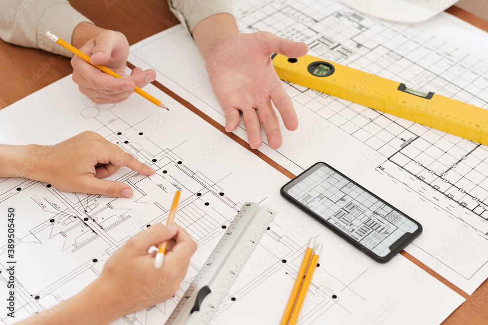 Hands of two young engineers with pencils over sketches of new construction Hands of two young engineers with pencils over sketches of new construction