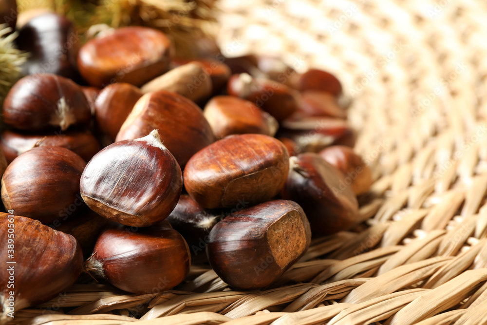 Fresh sweet edible chestnuts on wicker mat, closeup Fresh sweet edible chestnuts on wicker mat, closeup