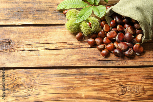 Fresh sweet edible chestnuts on wooden table, above view. Space for text