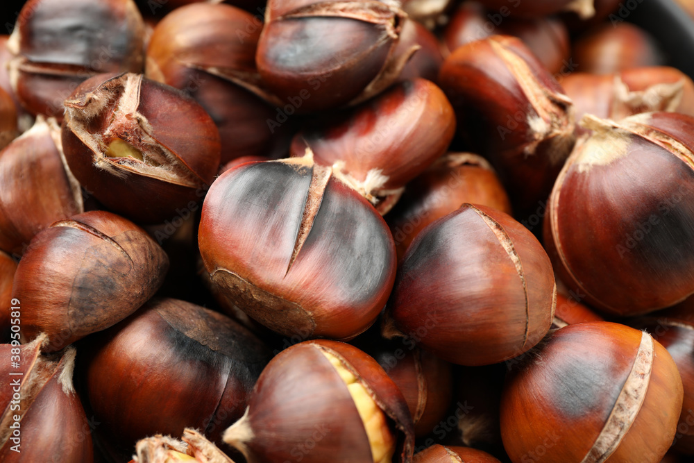 Obraz premium Pile of delicious edible roasted chestnuts as background, closeup