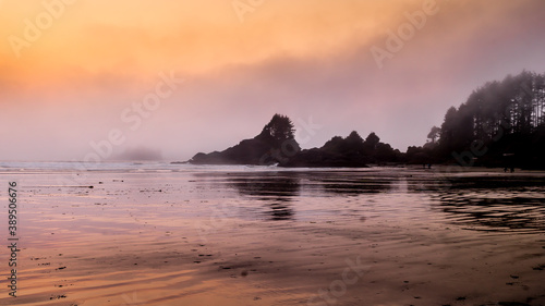 Sunset causing an Orange Glow over the Fog hanging over the rocky shore between Cox Bay and Chesterman Beach at the Pacific Rim National Park on Vancouver Island, British Columbia, Canada photo