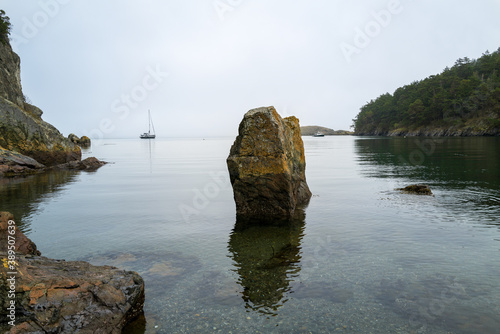 Two boats anchored on either side of a rock in Watmough Bay, Lopez Island, Washington, USA