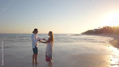Wide angle view of mature couple kissing on the beach at sunrise.