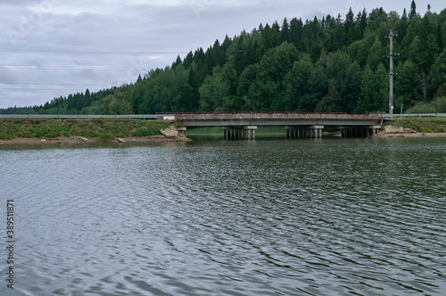 Small concrete bridge over the river or lake with dense forest on background