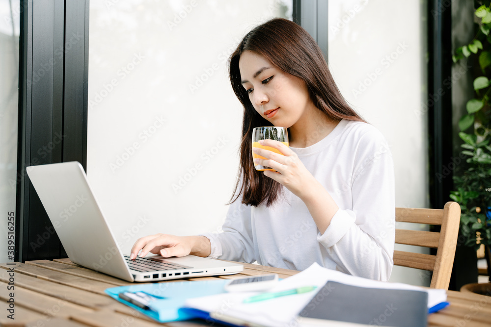 Asian woman in white shirt working with laptop and drinking orange juice. Asian woman in white shirt working with laptop and drinking orange juice.