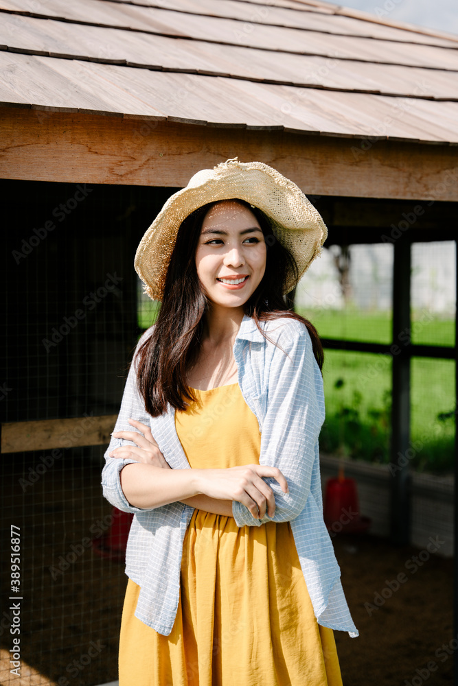 Asian farmer woman wear hat standing at coop animal in farmland.