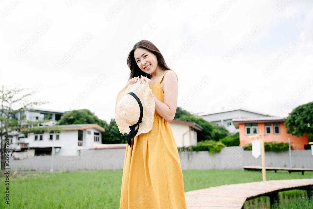 Obraz premium Beautiful asian traveler woman hold hat standing on wooden bridge across rice field.