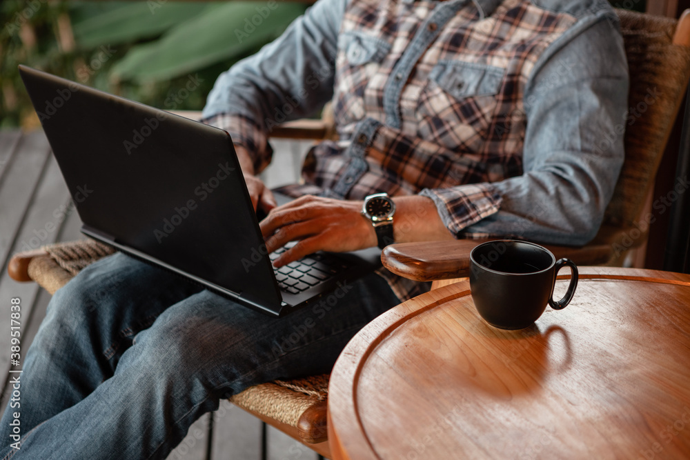 Male hand typing on laptop keyboard in office. Businessman, student, work from home, distance education, online learning, studying concept. Focus on the cup of coffee on the table Male hand typing on laptop keyboard in office. Businessman, student, work from home, distance education, online learning, studying concept. Focus on the cup of coffee on the table