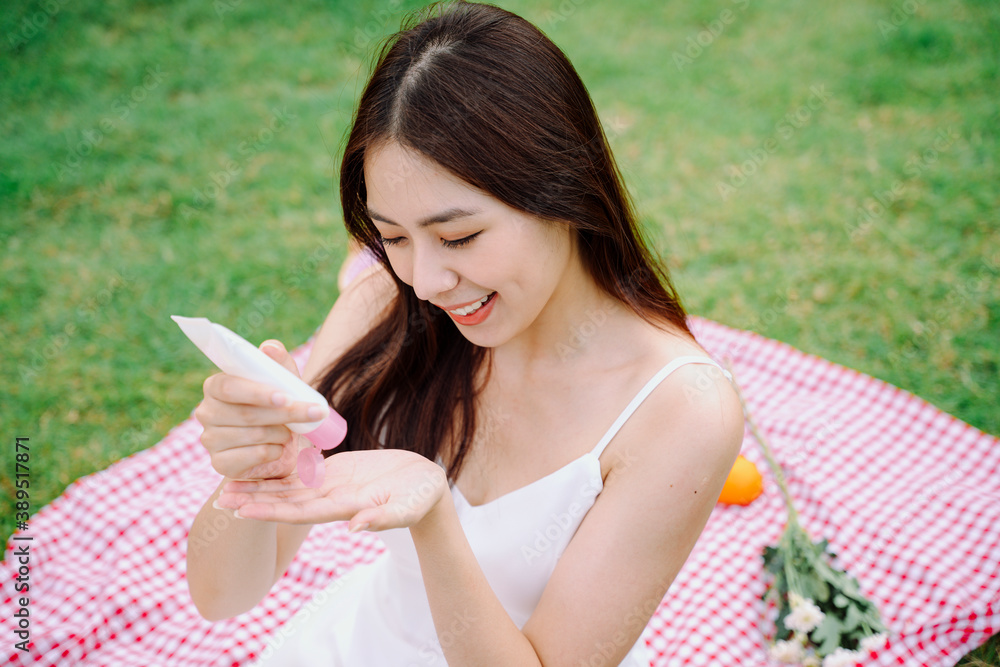 Asian traveler woman applying white skin lotion at park outdoors. Asian traveler woman applying white skin lotion at park outdoors.