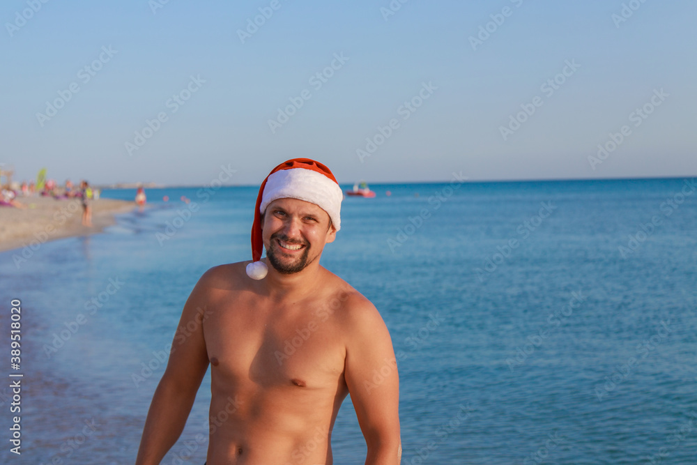 new year's eve on the beach by the sea. a man in a Christmas hat is sunbathing in the sun. blue sky like a copy space