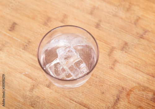 Looking down on a glass of clear water with ice on the table