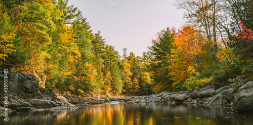 Fototapeta Naklejka Na Ścianę i Meble -  Long exposure photograph of water with a mirror like reflection of fall foliage colors in the Adirondacks, NY