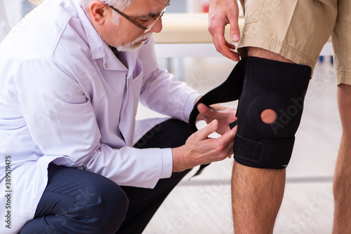 Experienced doctor traumatologist examining young male patient