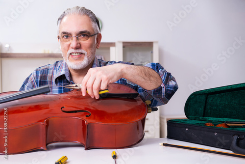 Obraz na plátně Senior male repairman repairing musical instruments at home