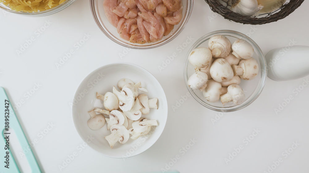Bowl of fresh raw organic mushrooms and bowl of chopped chicken fillet close up on white background. Bowl of fresh raw organic mushrooms and bowl of chopped chicken fillet close up on white background.