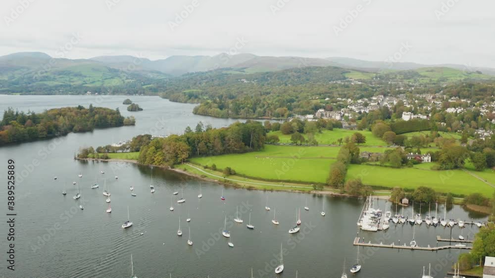 aerial shot from a drone of lake windermere in the foreground there are fields and the small town of bowness in the background you can see the mountains and hills of the Lake District aerial shot from a drone of lake windermere in the foreground there are fields and the small town of bowness in the background you can see the mountains and hills of the Lake District