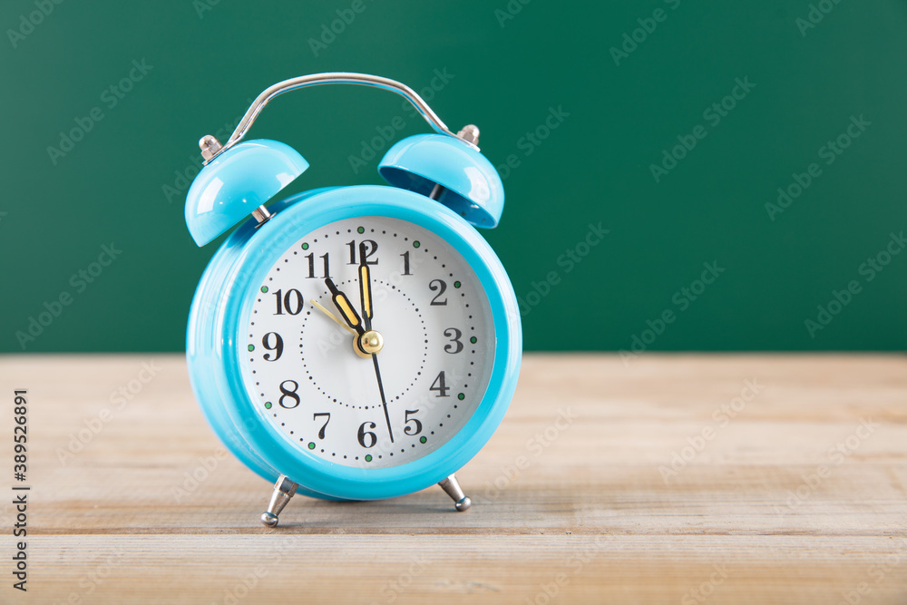 Teaching a blue alarm clock in front of blackboard Teaching a blue alarm clock in front of blackboard