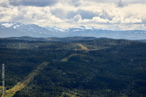 Power line gate in the Swedish Jämtland forests in the direction of high mountain peaks. Electricity line in the forest.